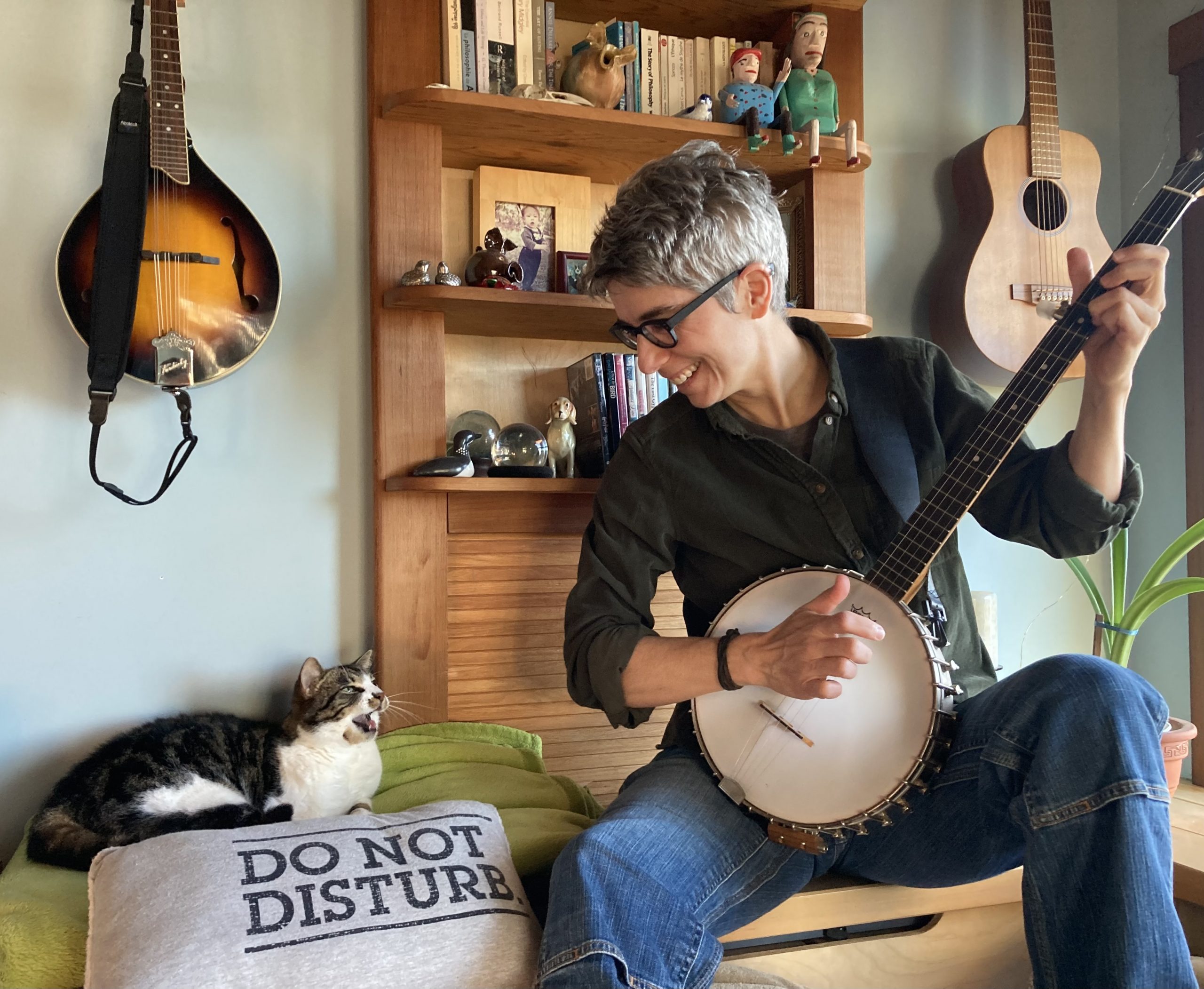 Dr. Caroline Shooner sitting with her cat while strumming a banjo